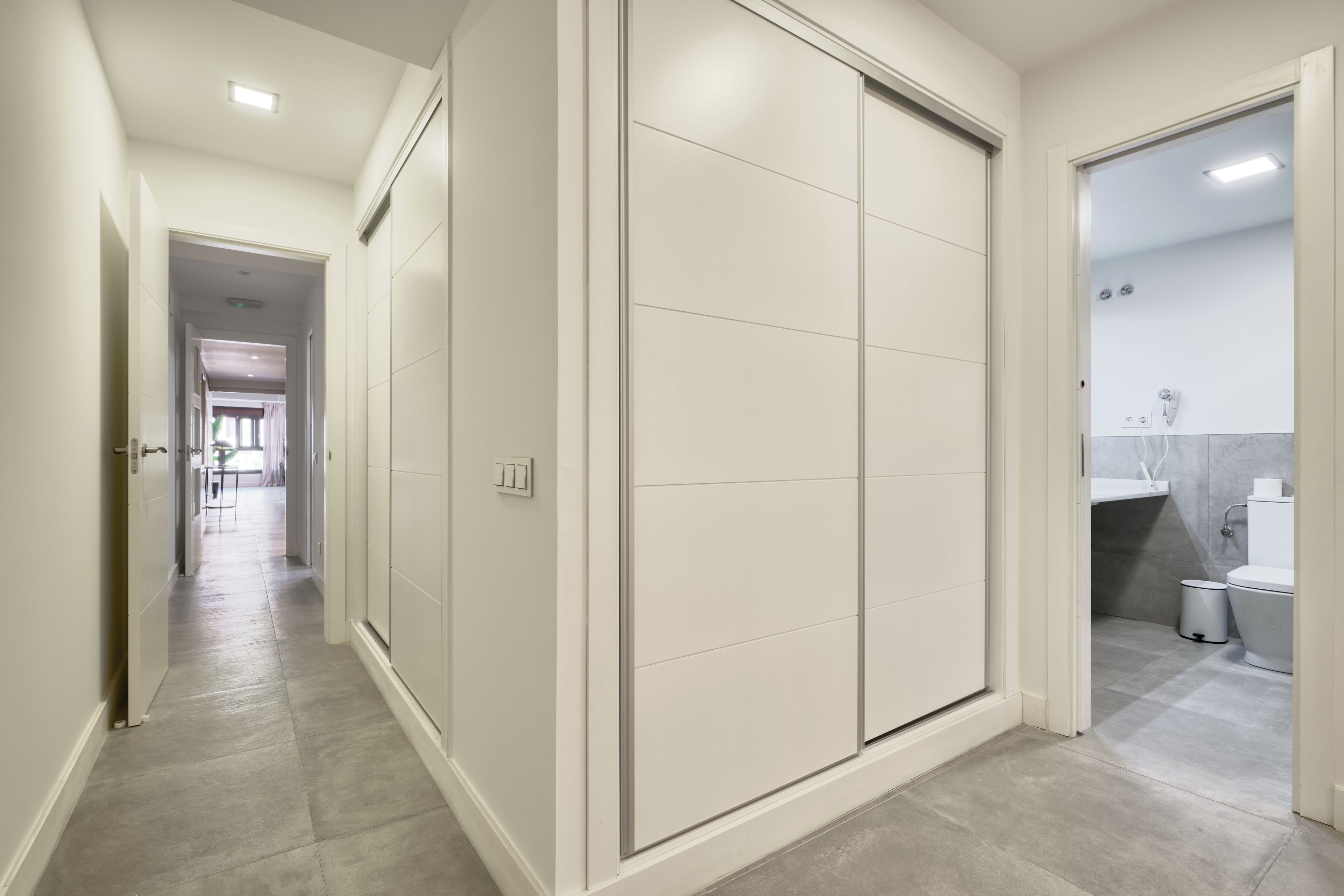 A hallway with a sliding door leading to a bathroom.