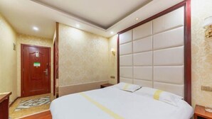 Una habitación de hotel con una cama grande, una puerta de madera y un papel tapiz estampado.