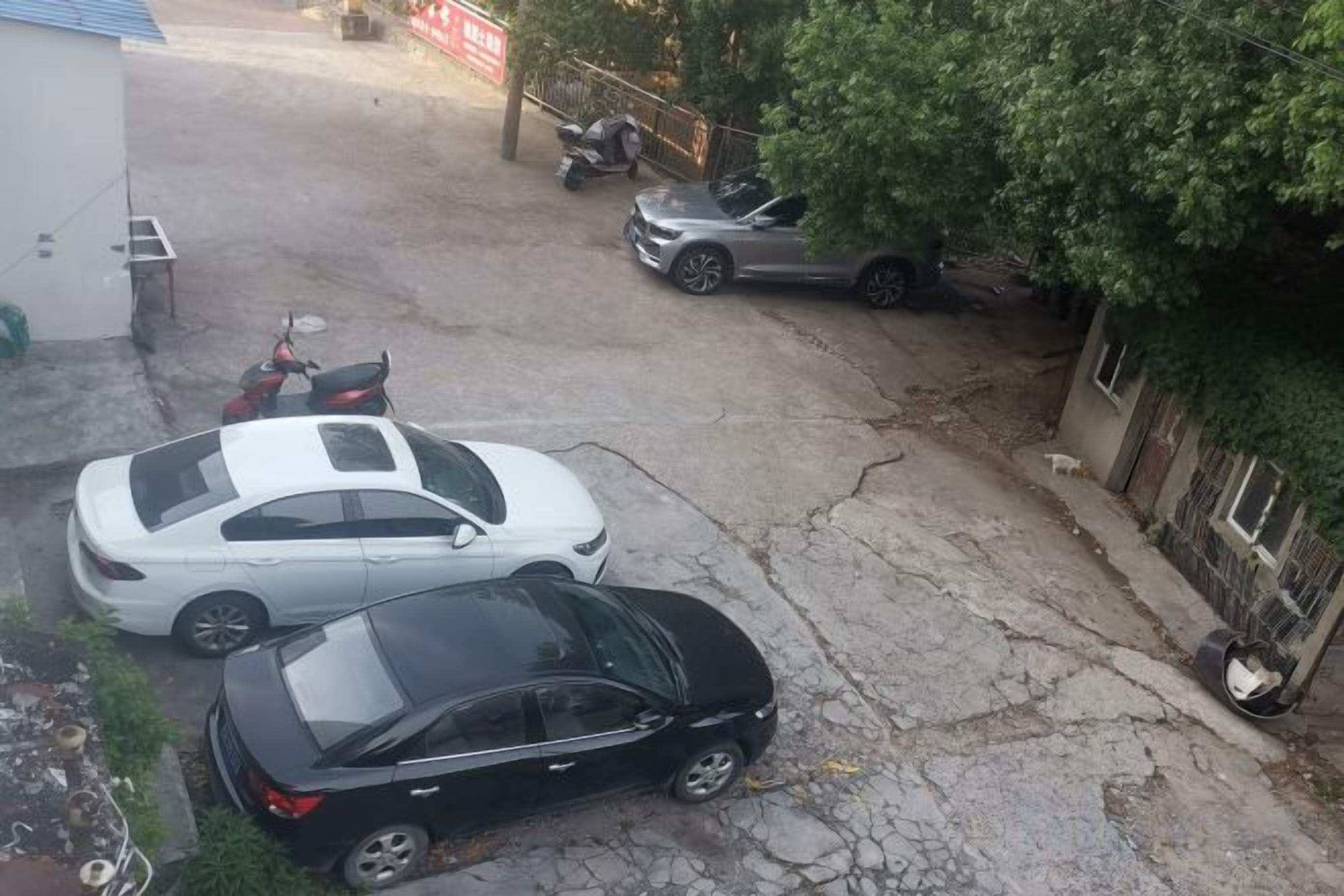 Un estacionamiento con dos coches y una motocicleta.