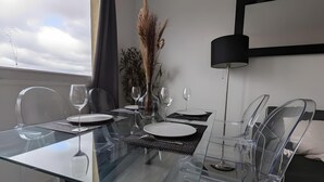 Un comedor moderno con una mesa de vidrio, sillas transparentes y un jarrón con plantas secas.