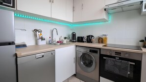 Una cocina moderna con armarios blancos, lavavajillas, lavadora y horno.