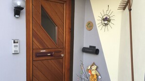 A wooden door with a glass panel, a mailbox, a wall-mounted light fixture, a sun-shaped decoration, and a garden statue. - Vacation apartment Philipp (Emmingen-Liptingen)