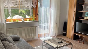 A living room with a sofa, a coffee table, a TV, and a window with curtains. - Vacation apartment Philipp (Emmingen-Liptingen)