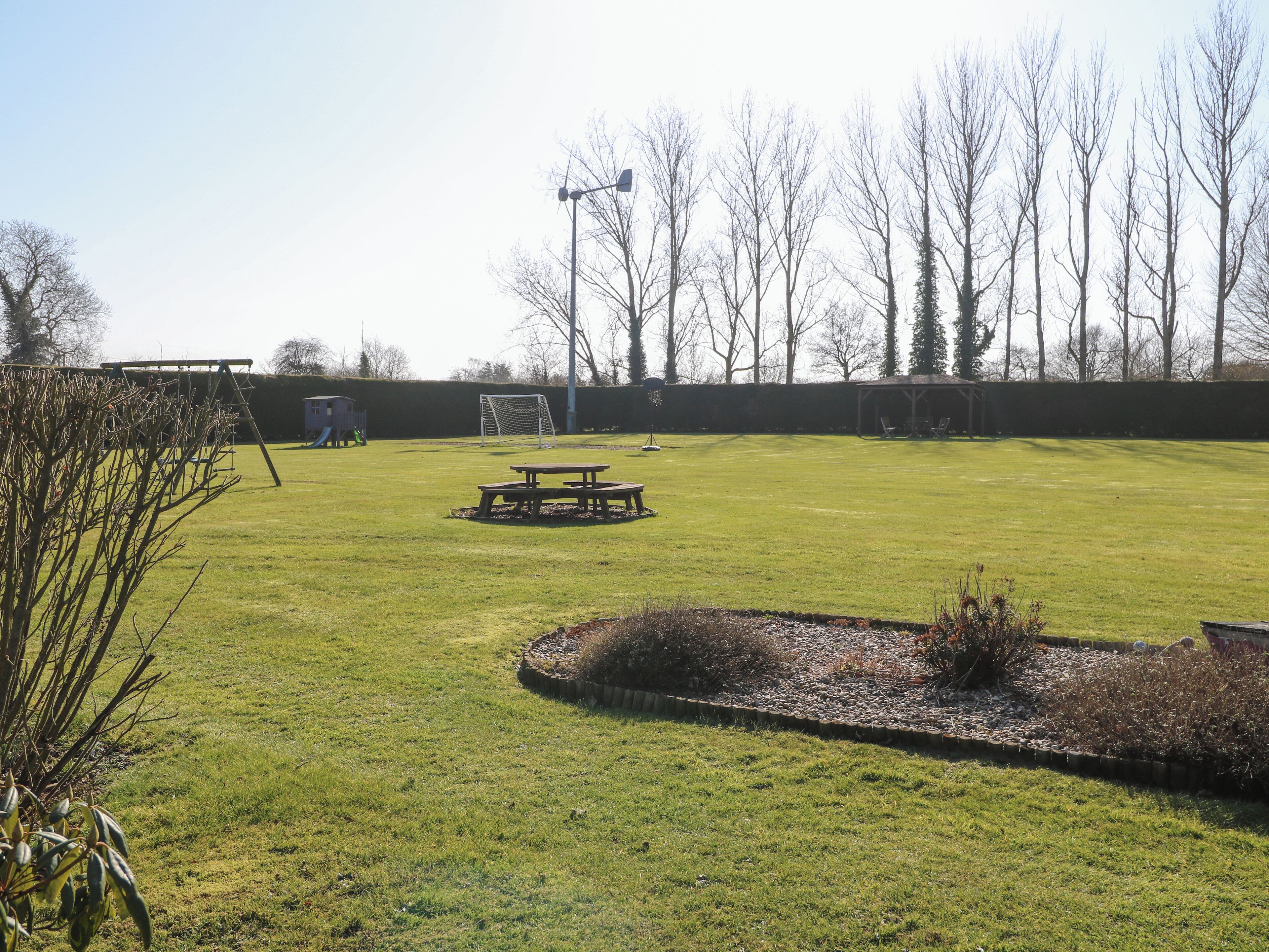 A grassy outdoor area with a picnic table, a soccer goal, and a play structure.