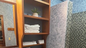 Ein Badezimmer mit Toilette, Waschbecken und Regalen mit Handtüchern.