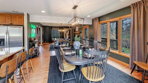 Una cocina moderna con comedor, armarios de madera y grandes ventanales.