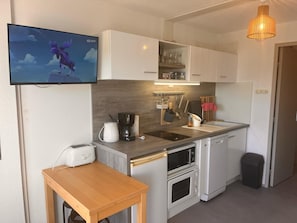 A compact kitchen with a coffee maker, toaster, microwave, and oven.
