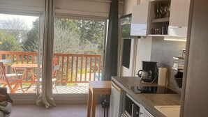 Una cucina moderna con zona pranzo, un balcone con mobili da esterno e un'ampia finestra.