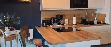 A modern kitchen with a wooden island, bar stools, and a built-in microwave.