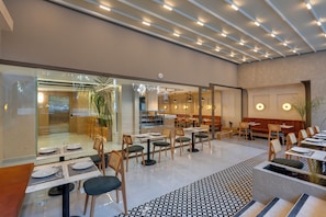 A modern restaurant with glass partitions, wooden furniture, and a patterned floor.