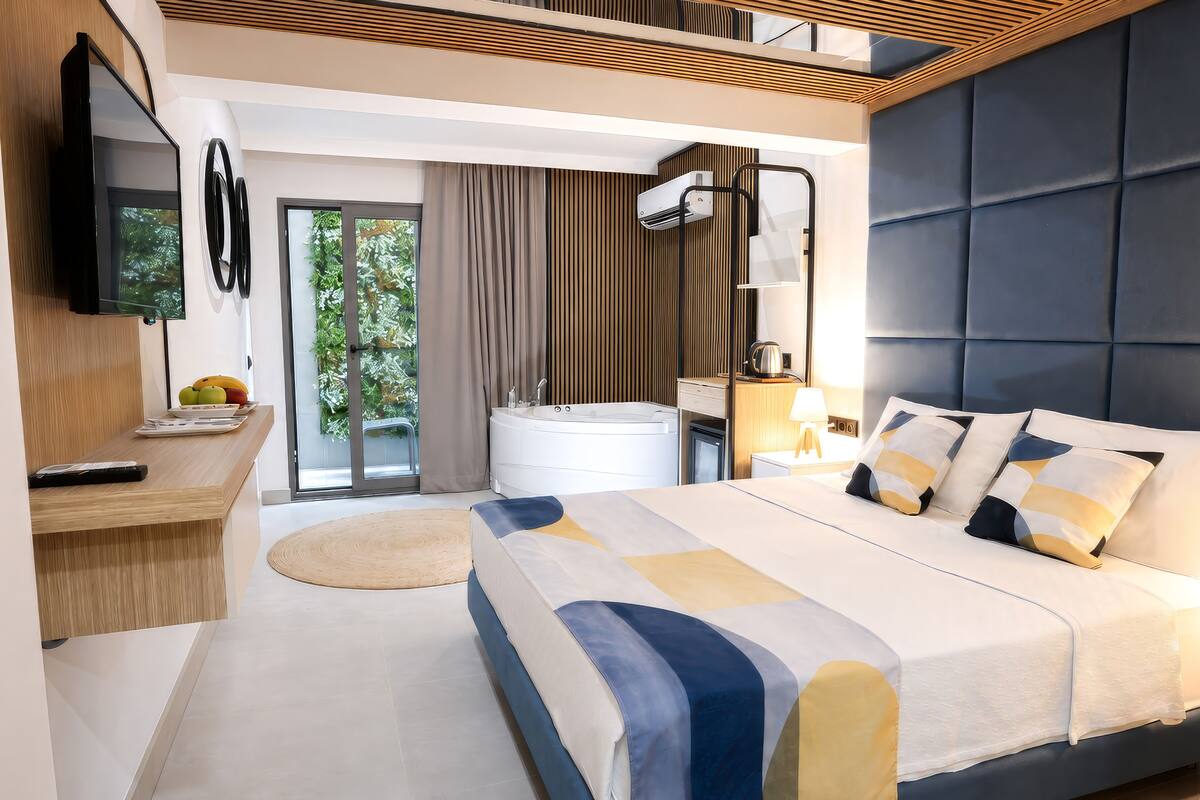 Une chambre d’hôtel moderne équipée d’un lit, d’un bureau, d’une télévision, d’une salle de bain et offrant une vue sur la verdure.