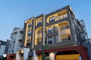 A multi-story hotel with balconies, a sign indicating it is a hotel, and a fire escape on the right side.