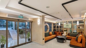 A hotel lobby with a reception desk, seating area, and large windows. - Mesona Hotels Blue Hill (Konyaalti)