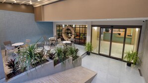A spacious indoor area with seating arrangements, potted plants, and a reception desk. - Mesona Hotels Blue Hill (Konyaalti)