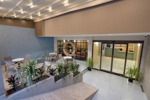 Un amplio espacio interior con asientos, plantas en macetas y una mesa de recepción.