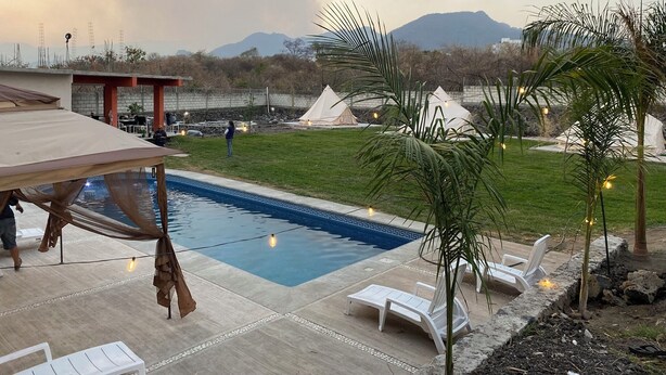 A pool area with lounge chairs, a hammock, and tents in the background. - Glamphouse, adventure and relaxation! (Oaxtepec)