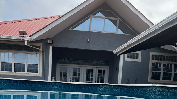 Una casa moderna con piscina, tejado rojo y un ventanal grande.