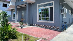 Una casa moderna de dos pisos con techo rojo, ventanas grandes y entrada pavimentada.
