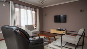 Una sala de estar con sofá, sillón, mesa de centro, televisor y aparador.