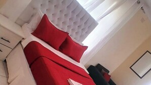 A hotel room with a bed, a desk, and a chair. - Marcifen (Harare)
