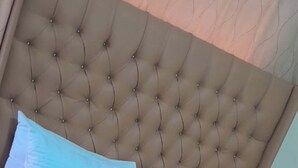 A neatly made bed with a tufted headboard, white linens, and a red accent. - Marcifen (Harare)