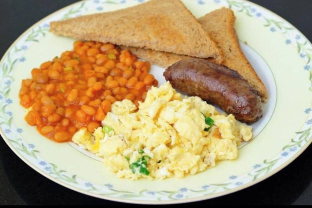 Ein Teller mit Toast, Bohnen, Rührei und Wurst.