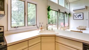 Una cocina moderna con ventanas amplias, encimera blanca y un lavamanos.
