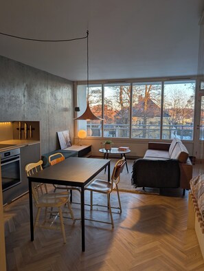 Enjoy a city view from the large window in this apartment's spacious living area, which features an oven and dining table.