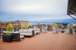 Eine Dachterrasse mit Außenmöbeln, Blick auf die Stadt und Lichterketten.