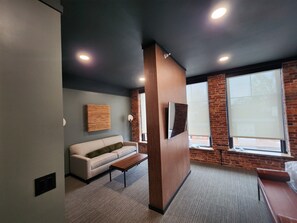 Ein modernes Zimmer mit einer Couch, einer Wand mit Holzpaneelen und einem großen Fenster.