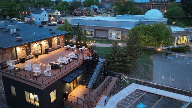 A rooftop patio with outdoor seating and a staircase leading to an upper level. - EXPLORE Marquette Historic District (Marquette)