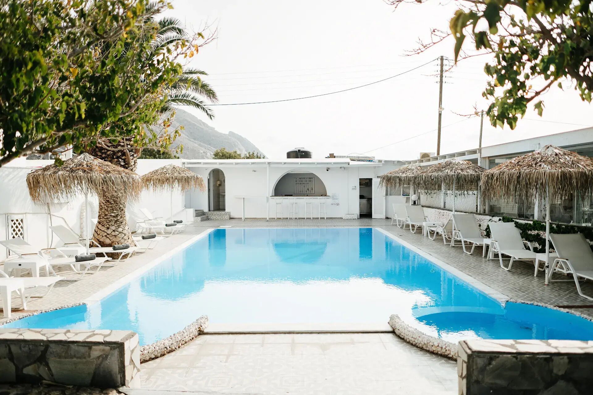 A pool area with lounge chairs and a bar.