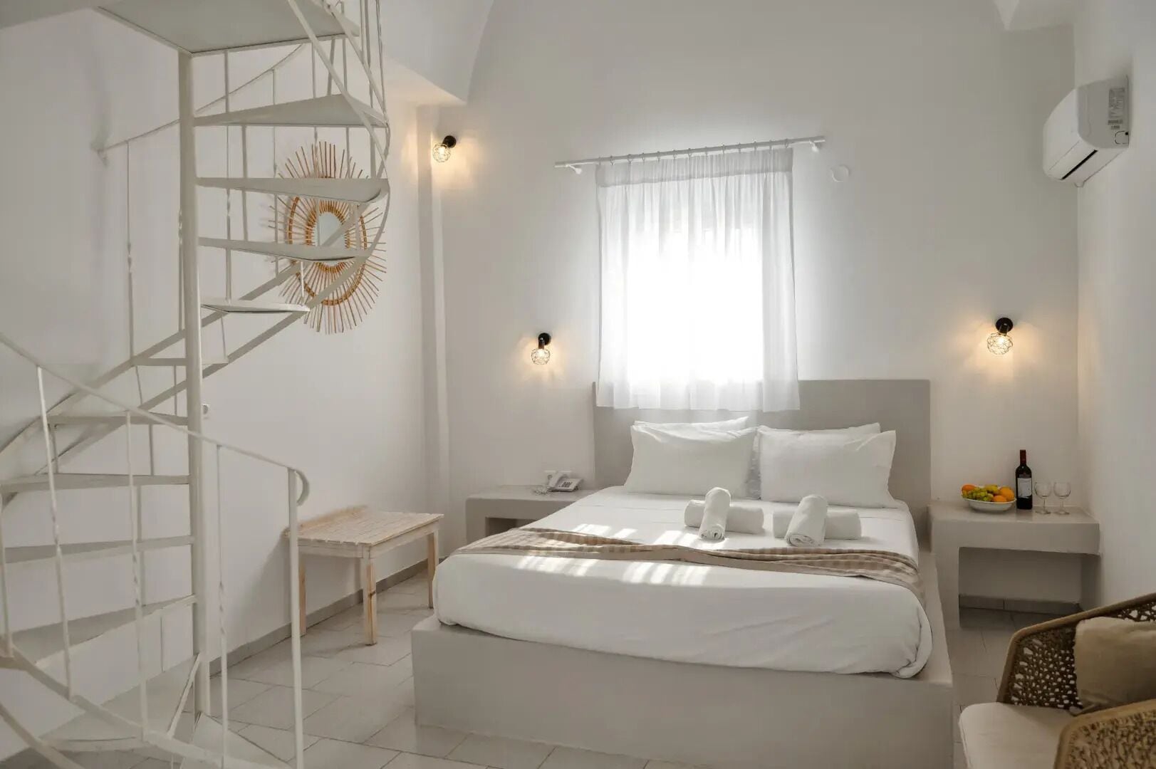 A modern bedroom with a large bed, a spiral staircase, and a small table.