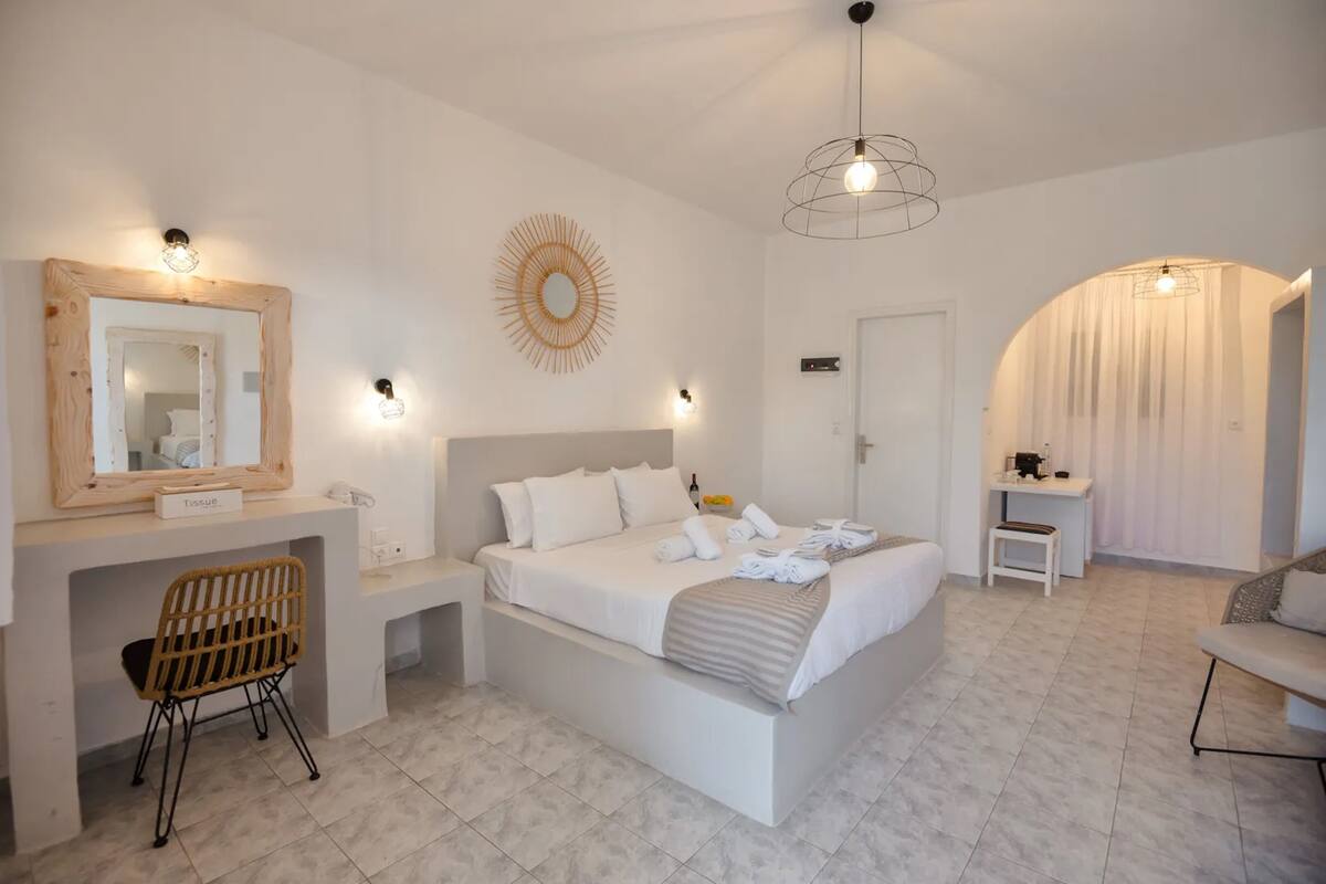 A modern bedroom with a large bed, bedside tables, a desk, and a chair.