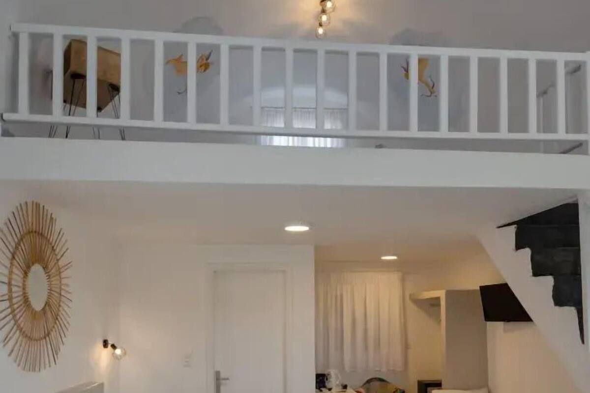 A hotel room with a large bed, a smaller bed, a desk, and a staircase.