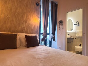 A hotel room with a bed, a window with curtains, a bathroom with a sink and mirror, and a wall-mounted hairdryer. - LaReginadelleLocazioni in Porta Romana 2 (Milan)