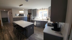 Una cocina moderna con una isla central, armarios oscuros y un horno empotrado.