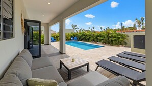 Un espacio exterior moderno con piscina, sofá y sillones de descanso.