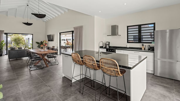 Una cocina moderna con una isla grande, electrodomésticos de acero inoxidable y un comedor con mesa y sillas.