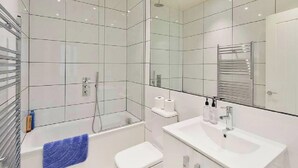 A modern bathroom with a glass shower enclosure, a white toilet, a sink with a mirror, and a towel rack.