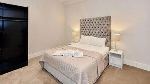 A neatly arranged bedroom with a large bed, a bedside table, and a wardrobe.