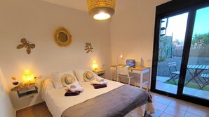 Une chambre à coucher avec un lit, des tables de chevet, un bureau et une vue sur l’extérieur.