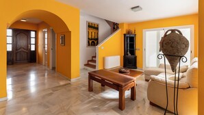 A living room with a wooden table, a beige sofa, and a staircase leading to another room. - Villa Paraíso in Mojácar with pool for 14 guests – 7 bedrooms – 3.5 bathrooms (Mojácar)