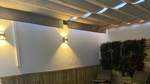 Un espacio al aire libre techado con piscina, césped artificial y mobiliario.