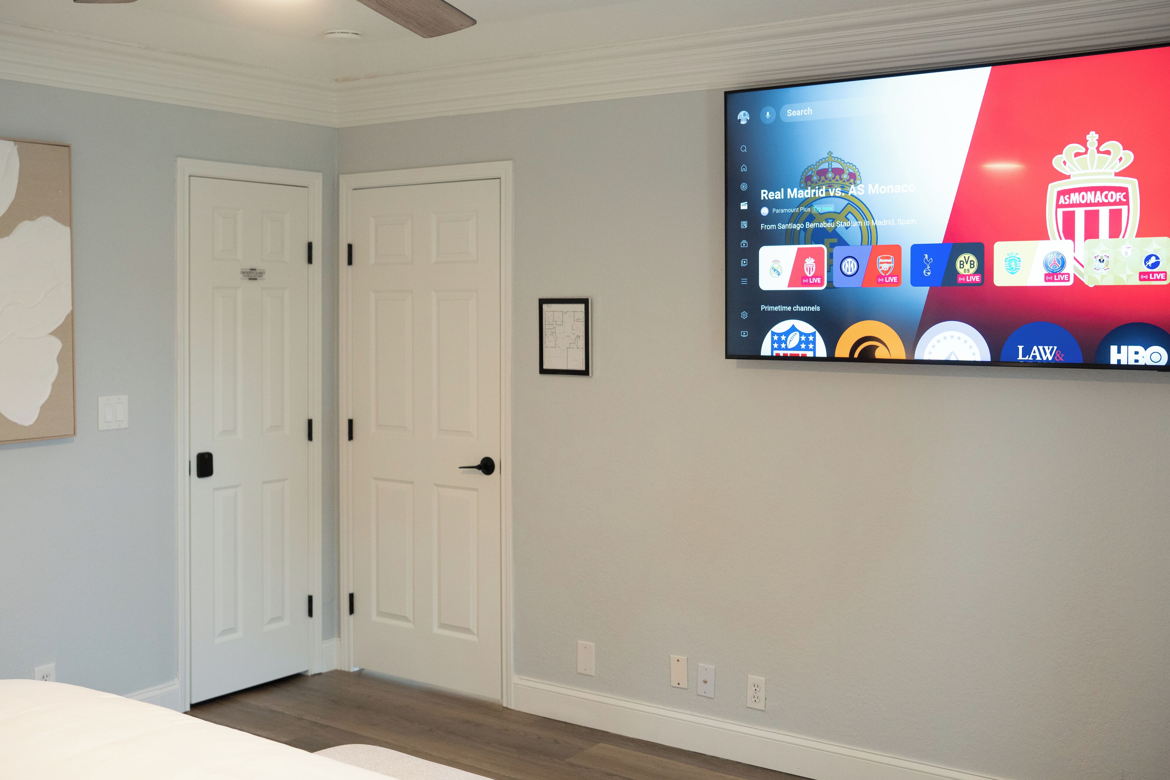 A hotel room with a large flat-screen TV mounted on the wall displaying a sports channel interface.