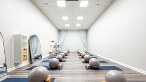 Ein Raum mit in Reihen auf Matten angeordneten Gymnastikbällen, einem weißen Regal und einem Spiegel links.