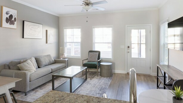 A living room with a grey sofa, a coffee table, a chair, and a TV stand.