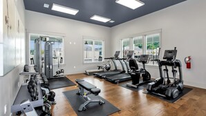 Ein Fitnessstudio mit Laufbändern, Crosstrainern und Kurzhanteln.