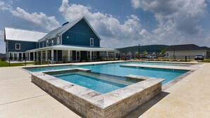 A rectangular swimming pool with a stone border, surrounded by a paved area.