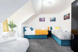 Quarto de hotel moderno com duas camas, uma mesinha e um vaso de planta.
